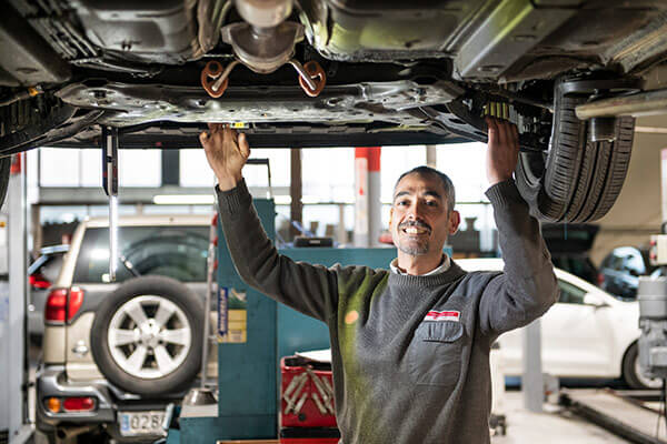 mecánico debajo de un coche revisandolo